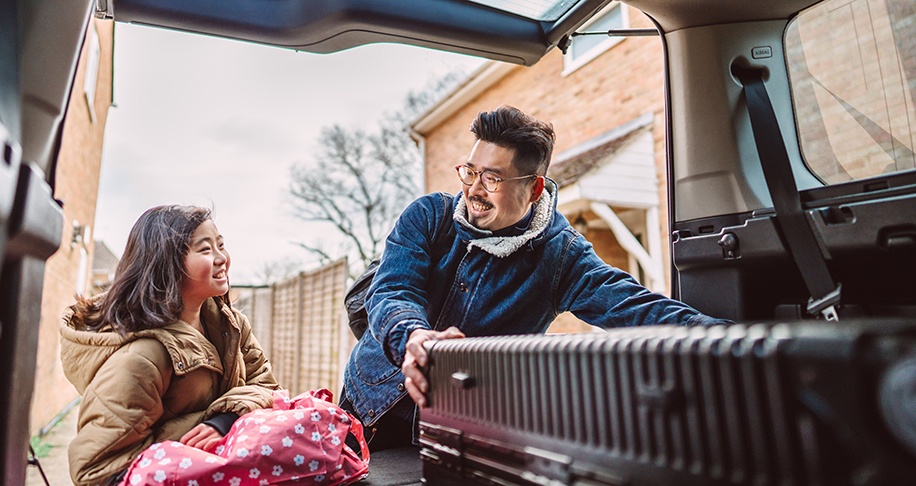 father and daughter putting luggage in the boot